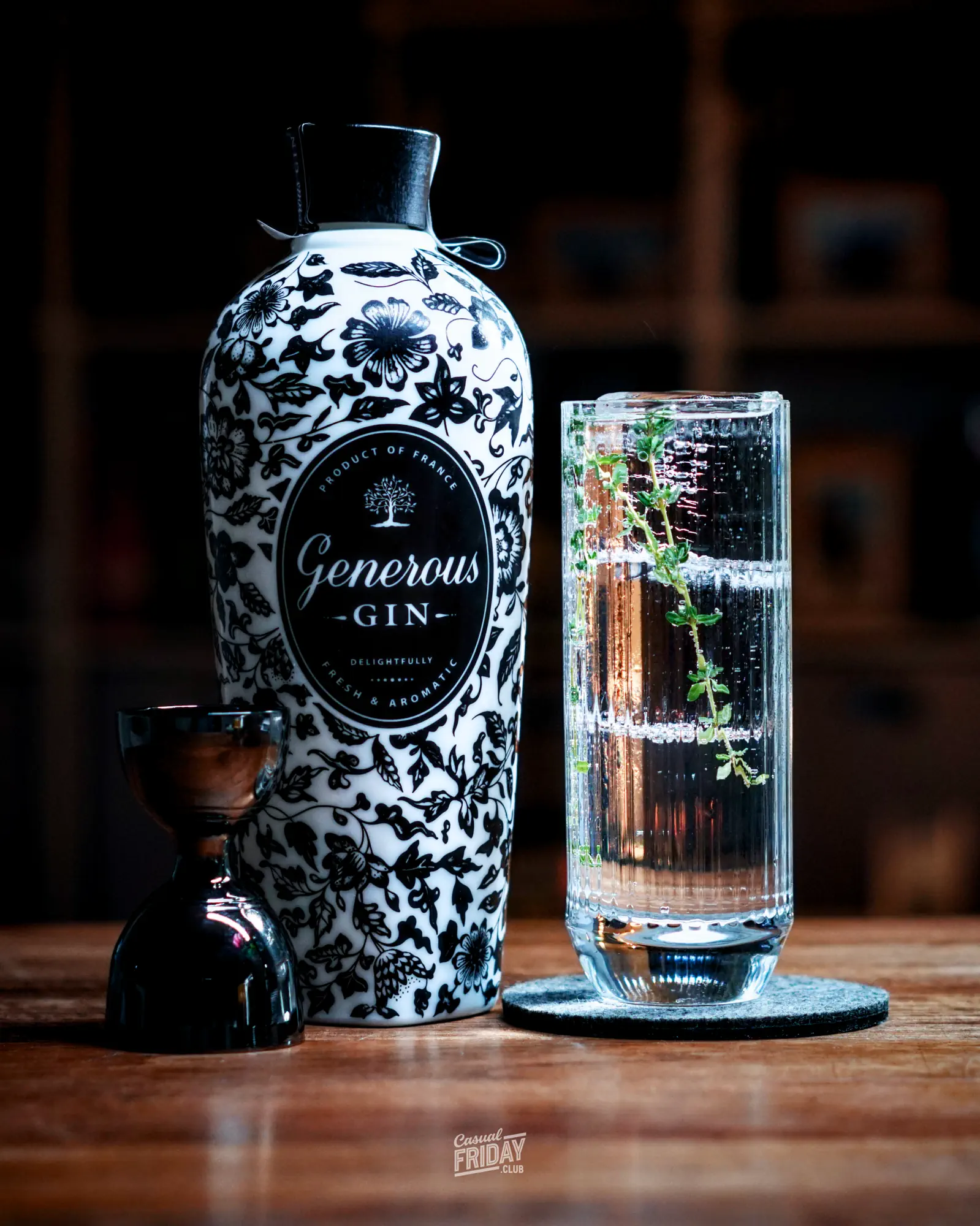 generous gin served in a highball glass with tonic, clear ice and garnish on a wooden table top