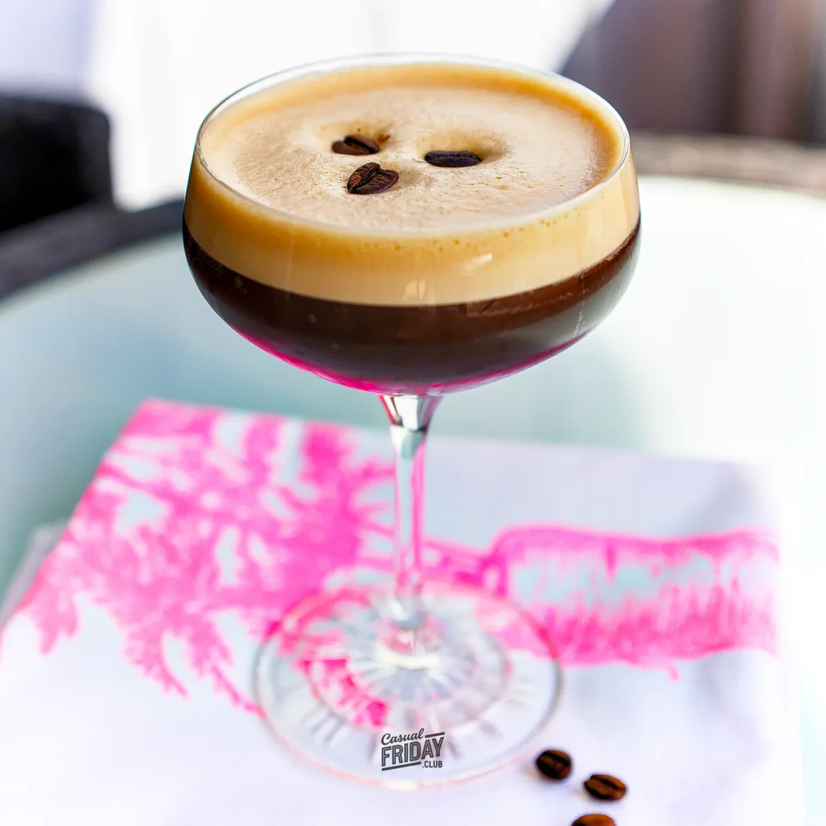 An Espresso Martini cocktail in a Nick and Nora glass on a vibrant napkin in the sun