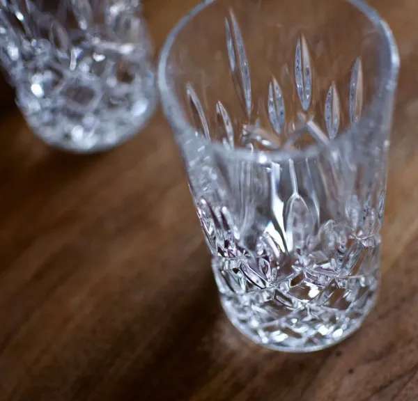 A crystal long drink glass for gin tonic with delicate cross-hatched patterns placed on a table